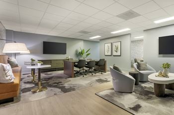 A modern business center with a variety of seating options and a flat screen TV mounted on the wall at The Vue in San Pedro, CA